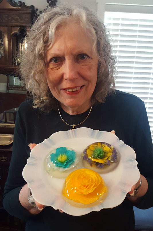 Susan Hood holding a plate with 3 gelatin art desserts.